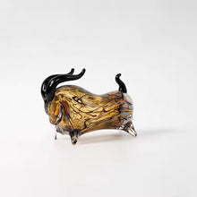 Load image into Gallery viewer, Decorative bull sculptures on books with a candle against a textured white wall. Rex Decorative Bull by Allthingscurated are meticulously handmade from high quality glass. Comes in three striking finishes—an all-all black edition or two-tone variants featuring bold graphic elements. Rex brings contemporary flair and bold energy to any room. More than décor, it’s an ideal gift for those born under the Ox zodiac and Taurus sign. Shown here is the Amber Black bull.