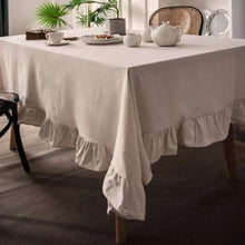 Load image into Gallery viewer, Introducing Ruffled Cotton Tablecloth by Allthingscurated. Made from 100% cotton, our tablecloth exudes French country charm with its romantic, frilly ruffles. With the perfect balance of decorative and laid-back, they have a welcoming and comforting vibe. Available in 8 solid colors. Featured here is the beige tablecloth.