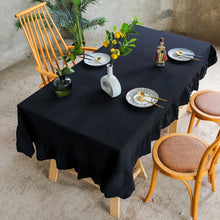 Load image into Gallery viewer, Introducing Ruffled Cotton Tablecloth by Allthingscurated. Made from 100% cotton, our tablecloth exudes French country charm with its romantic, frilly ruffles. With the perfect balance of decorative and laid-back, they have a welcoming and comforting vibe. Available in 8 solid colors. Featured here is the Black tablecloth.