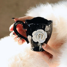 Load image into Gallery viewer, This Camellia Porcelain Cup Set / Mug by Allthingscurated features a single, significant bloom in a timeless black and white design that exudes sophistication. Its high fashion appeal makes it a perfect gift or impressive addition to your high-tea gatherings. Available as a mug or a cup set.