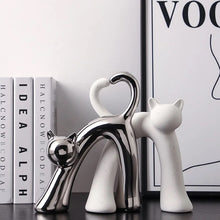 Load image into Gallery viewer, These Cat Couple Love Figurines by Allthingscurated are perfect for cat lovers. Made of ceramic, they feature a pair of cute and whimsical cats in contrasting colors, with their tails entwined to form a heart shape. A romantic and unique gift for any occasion.