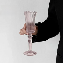 Load image into Gallery viewer, Cecily Flute Glasses by Allthingscurated feature a medieval-inspired vertical ridged design that provides a unique texture with an elegant touch. The long, sturdy stem ensures a steady hold while the jewel tones add a touch of sophistication to any celebration. Designed to complement your favorite wines, these glasses are perfect for entertaining and will brighten up any table. Featured here is flute glass in Light Pink.