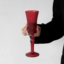 Load image into Gallery viewer, Cecily Flute Glasses by Allthingscurated feature a medieval-inspired vertical ridged design that provides a unique texture with an elegant touch. The long, sturdy stem ensures a steady hold while the jewel tones add a touch of sophistication to any celebration. Designed to complement your favorite wines, these glasses are perfect for entertaining and will brighten up any table. Featured here is flute glass in Red.