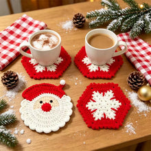 Load image into Gallery viewer, Red and white crochet coasters in two different designs—Santa Claus and Snowflake on a wooden table decorated with pinecones, artificial snow, pine needles and gingham kitchen towels, and two hot chocolate drinks.