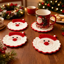 Load image into Gallery viewer, Santa Claus design crochet coasters laid on a wooden table, with a Christmas wreath and some cookies, and a lighted Christmas in the background.
