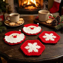 Load image into Gallery viewer, Red and white crochet coasters in two different designs—Santa Claus and Snowflake on a dark wood round table decorated with pinecones, pine needles and two hot chocolate drinks with cookies on the plate. Background shows a fireplace.