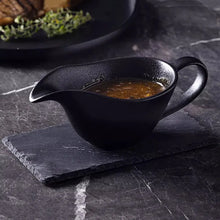 Load image into Gallery viewer, Curtis Ceramic Gravy Boat by Allthingscurated features an easy-to-hold handle and a narrow spout to ensure precise pouring without spills and drips. Available in white with a smooth, shiny glaze or black with a matte, rough finish. This versatile serveware with a capacity of 220ml or 7.4 fluid ounce is perfect for any occasion, formal or casual.