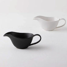 Load image into Gallery viewer, Curtis Ceramic Gravy Boat by Allthingscurated features an easy-to-hold handle and a narrow spout to ensure precise pouring without spills and drips. Available in white with a smooth, shiny glaze or black with a matte, rough finish. This versatile serveware with a capacity of 220ml or 7.4 fluid ounce is perfect for any occasion, formal or casual.