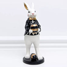 Load image into Gallery viewer, Our Regal Rabbit Family Figurines by Allthingscurated are beautifully-crafted and decorative. Made high-quality resin, these unique figurines will add a touch of elegance and whimsy to your home décor. Available in 6 designs, they are the perfect additions to your spring and Easter decorations. Featured here is Egg Holding Rabbit.
