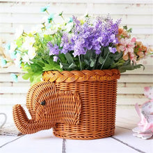Load image into Gallery viewer, Wicker elephant-shaped basket with flowers on a wooden surface by Allthingscurated.