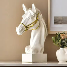 Load image into Gallery viewer, White horse head sculpture with gold bridle on a white base against a beige wall. Fargo Horse Head Bust by Allthingscurated is an elegant decorative sculpture with meticulous detail and flaunts a gorgeous gold-accented bridle. Perfect for horse enthusiasts and makes a meaningful gift for those born under the Horse zodiac sign. And expertly crafted to complement both timeless classic and contemporary modern interiors.