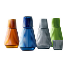 Load image into Gallery viewer, Hanis Fluted Bedside Water Carafe by Allthingscurated has a generous capacity of 1000 ml or 33.8 fluid ounce. Its minimalist design boats a fluted body and distinctive conical shape, making it a stylish drinkware that is also a beautiful home décor piece. Crafted from durable, heat-resistant glass for long-lasting use. Choose from 4 stunning colors in Amber, Blue, Green and Black. Each carafe comes with matching cover that doubles as a drinking cup.
