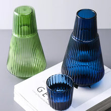 Load image into Gallery viewer, Hanis Fluted Bedside Water Carafe by Allthingscurated has a generous capacity of 1000 ml or 33.8 fluid ounce. Its minimalist design boats a fluted body and distinctive conical shape, making it a stylish drinkware that is also a beautiful home décor piece. Crafted from durable, heat-resistant glass for long-lasting use. Choose from 4 stunning colors in Amber, Blue, Green and Black. Each carafe comes with matching cover that doubles as a drinking cup.