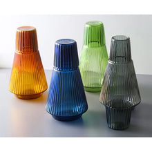 Load image into Gallery viewer, Hanis Fluted Bedside Water Carafe by Allthingscurated has a generous capacity of 1000 ml or 33.8 fluid ounce. Its minimalist design boats a fluted body and distinctive conical shape, making it a stylish drinkware that is also a beautiful home décor piece. Crafted from durable, heat-resistant glass for long-lasting use. Choose from 4 stunning colors in Amber, Blue, Green and Black. Each carafe comes with matching cover that doubles as a drinking cup.
