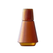 Load image into Gallery viewer, Hanis Fluted Bedside Water Carafe by Allthingscurated has a generous capacity of 1000 ml or 33.8 fluid ounce. Its minimalist design boats a fluted body and distinctive conical shape, making it a stylish drinkware that is also a beautiful home décor piece. Crafted from durable, heat-resistant glass for long-lasting use. Choose from 4 stunning colors in Amber, Blue, Green and Black. Each carafe comes with matching cover that doubles as a drinking cup. Featured here is carafe in Amber.