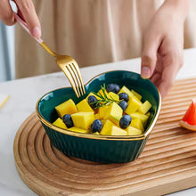 Load image into Gallery viewer, Teal heart shape bowl with fruit on a wooden board. Gold-rimmed Heart Shape Ceramic Bowl by Allthingscurated is a beautiful and versatile piece to own in your dinnerware collection. Perfect for salads, desserts and appetizers, its charming design adds an extra touch of romance for Valentine’s Day dinner; and make everyday meals extra special.
