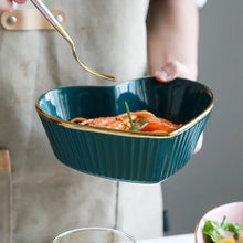 Load image into Gallery viewer, Person holding a teal bowl with gold rim containing food, blurred background. Gold-rimmed Heart Shape Ceramic Bowl by Allthingscurated is a beautiful and versatile piece to own in your dinnerware collection. Perfect for salads, desserts and appetizers, its charming design adds an extra touch of romance for Valentine’s Day dinner; and make everyday meals extra special.