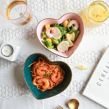 Load image into Gallery viewer, Heart-shaped bowls with pasta and salad on a textured surface with glasses and a candle.