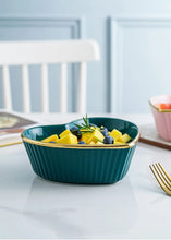 Load image into Gallery viewer, Teal heart shape bowl with gold rim containing fruit on a white table. Gold-rimmed Heart Shape Ceramic Bowl by Allthingscurated is a beautiful and versatile piece to own in your dinnerware collection. Perfect for salads, desserts and appetizers, its charming design adds an extra touch of romance for Valentine’s Day dinner; and make everyday meals extra special.