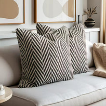 Load image into Gallery viewer, Herringbone pattern pillows on a sofa with abstract art in the background by Allthingscurated