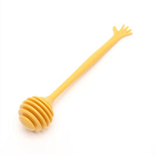 Load image into Gallery viewer, Pastel Hand Wand Honey Dippers by Allthingscurated come in 4 charming pastel colors of blue, pink, yellow and white. The unique dipper features a long handle that ends with a hand design at the tip. Made of high-quality material for durability and practical use, the rounded head with deep grooves makes for optimal dispensing, perfect for honey toasts and drinks. Featured here is honey dipper in yellow.