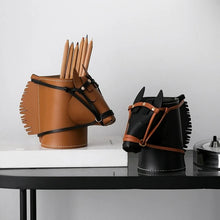 Load image into Gallery viewer, Two horse-shaped holders on a black table against a white wall, one in brown leather and one in black leather, both with brown leather bridle details and holding wooden pencils.