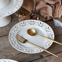 Load image into Gallery viewer, Juliette White Lace Dinnerware by Allthingscurated adds an elegant touch to your tabletop. This sophisticated set is crafted out of ceramic with a beautiful embossed lace rim, giving it a vintage touch. The creamy white pieces come in a dinner plate and cake stand in 2 sizes for easy mixing and matching. They are perfectly sized for a main course, starters and desserts.