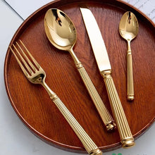 Load image into Gallery viewer, Julius Gold Stainless Steel Flatware Sets by Allthingscurated are crafted from high-quality 18/10 stainless steel. The weighty and solid construction provides a luxurious feel, while the Roman column handle design adds a touch of elegance. The mirror polished surface reflects a bright and shiny finish, adding a touch of sophistication to any table.