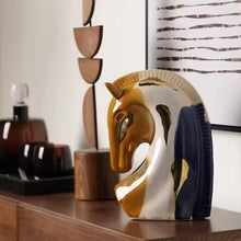 Load image into Gallery viewer, Decorative horse head sculpture on a wooden shelf with abstract wall art in the background. Jyunma Ceramic Horse by Allthingscurated is handmade artistry at its finest. It’s more than just decoration, it embodies auspiciousness and prosperity; represents steadfast loyalty and protective guardianship through time. Its elegance makes it a perfect gift for any horse enthusiasts or anyone born under the Chinese zodiac sign of the horse; and an exquisite addition to any contemporary home for its enduring appeal.