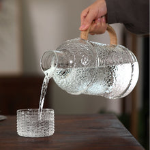 Load image into Gallery viewer, Kiv Hammered Glass Pitcher with Cover in 2 liter or 68 ounce capacity by Allthingscurated. Comes with a hemp rope handle for a rustic vibe. Large capacity and heat-resistant. It's the perfect thirst quencher for summer.