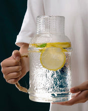 Load image into Gallery viewer, Kiv Hammered Glass Pitcher with Cover in 2 liter or 68 ounce capacity by Allthingscurated. Comes with a hemp rope handle for a rustic vibe. Large capacity and heat-resistant. It's the perfect thirst quencher for summer.