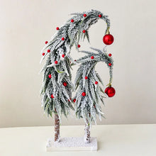 Load image into Gallery viewer, Snow Flocked Grinch Christmas Trees by Allthingscurated feature bending trees with a touch of quirkiness. The abstract design is both unconventional and whimsical. These snow-covered trees are decorated with crimson red baubles that will transform your home into a winter wonderland. Available in 2 sizes.
