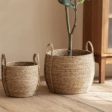 Load image into Gallery viewer, Leedon Woven Baskets by Allthingscurated are hand-woven from seagrass which is an eco-friendly material. The baskets feature sturdy handles for easy transportation and lend a rustic charm to any space. Perfect for storing household items or displaying your favorite plants. Available in 3 sizes.