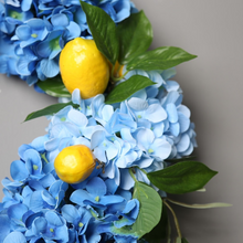 Load image into Gallery viewer, Summer Lemon Hydrangea wreath by Allthingscurated features a vibrant and cheerful yellow and blue color scheme, evoking images of sunny blue skies and warm summer days. The wreath adds a pop of color to your door and bring a little extra happiness to your home.
