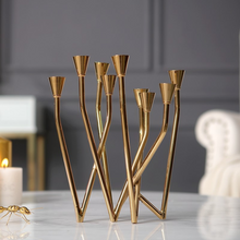 Load image into Gallery viewer, Lysa Gold Candelabra by Allthingscurated spots an asymmetrical design and clean lines that exude modern elegance. With 9 arms for taper candles, the gold-tone metal surface reflects the glow of the flames, creating a warm and captivating atmosphere. It’s stunning centerpiece for any occasion and decorative accent for any event or space.