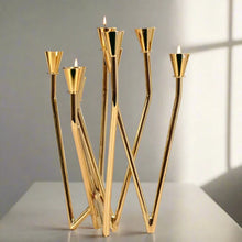 Load image into Gallery viewer, Lysa Gold Candelabra by Allthingscurated spots an asymmetrical design and clean lines that exude modern elegance. With 9 arms for taper candles, the gold-tone metal surface reflects the glow of the flames, creating a warm and captivating atmosphere. It’s stunning centerpiece for any occasion and decorative accent for any event or space.