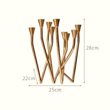 Load image into Gallery viewer, Lysa Gold Candelabra by Allthingscurated spots an asymmetrical design and clean lines that exude modern elegance. With 9 arms for taper candles, the gold-tone metal surface reflects the glow of the flames, creating a warm and captivating atmosphere. It’s stunning centerpiece for any occasion and decorative accent for any event or space. Measuring 25cm or 9.8 inches in length, 28cm or 11 inches in height and 22cm or 8.6 inches in width.