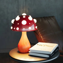 Load image into Gallery viewer, Whimsical Mushroom LED Lamp by Allthingscurated is unique and decorative, yet functional. The enchanting design features a playful mushroom silhouette, complete with red-capped spots lampshade to bring a touch of whimsy to any room. It makes a perfect gift for someone with a special affinity for mushrooms. Comes in a cordless and corded version with 2 lamp base colors. Featured here is the large lamp with woody base.