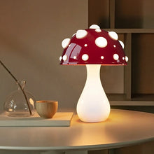 Load image into Gallery viewer, Whimsical Mushroom LED Lamp by Allthingscurated is unique and decorative, yet functional. The enchanting design features a playful mushroom silhouette, complete with red-capped spots lampshade to bring a touch of whimsy to any room. It makes a perfect gift for someone with a special affinity for mushrooms. Comes in a cordless and corded version with 2 lamp base colors. Featured here is the large lamp with white base.