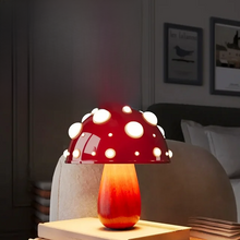 Load image into Gallery viewer, Whimsical Mushroom LED Lamp by Allthingscurated is unique and decorative, yet functional. The enchanting design features a playful mushroom silhouette, complete with red-capped spots lampshade to bring a touch of whimsy to any room. It makes a perfect gift for someone with a special affinity for mushrooms. Comes in a cordless and corded version with 2 lamp base colors. Featured here is the small lamp with woody base.