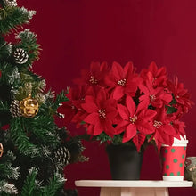 Load image into Gallery viewer, Red poinsettia plant with a Christmas tree and gift box on a red background. Bring the true spirit of the holidays into your home with this bundle of 5 classic red Faux Poinsettia by Allthingscurated. These timeless blooms complement any festive palette and instantly evokes Christmas cheer.