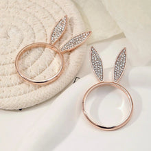 Load image into Gallery viewer, These sparkling Bunny Ear Napkin Rings (set of 6) by Allthingscurated add a cute and whimsical touch to your Easter table setting. Made of metal and encrusted with rhinestones, they come in gold, silver, and rose gold. Elevate your dining experience with these charming and sparkly napkin rings.