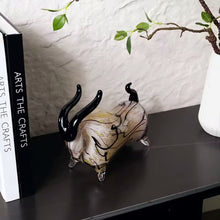 Load image into Gallery viewer, Decorative bull figurine with black horns on a dark surface, next to two books. Rex Decorative Bull by Allthingscurated are meticulously handmade from high quality glass. Comes in three striking finishes—an all-all black edition or two-tone variants featuring bold graphic elements. Rex brings contemporary flair and bold energy to any room. More than décor, it’s an ideal gift for those born under the Ox zodiac and Taurus sign.
