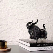 Load image into Gallery viewer, Black bull figurine on a stack of books with a textured white wall background. Rex Decorative Bull by Allthingscurated are meticulously handmade from high quality glass. Comes in three striking finishes—an all-all black edition or two-tone variants featuring bold graphic elements. Rex brings contemporary flair and bold energy to any room. More than décor, it’s an ideal gift for those born under the Ox zodiac and Taurus sign.