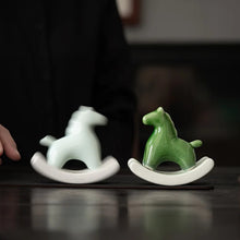 Load image into Gallery viewer, This Petite Ceramic Rocking Horse by Allthingscurated is a work of art. Crafted by hand from ceramic and decorated with a beautiful crackle pattern, it exudes a subtle far-eastern beauty and grace. Makes a perfect gift for those who appreciate quality craftsmanship and a treasured gift to any horse collector. Comes in green and azurerish white. Measures 9.8cm or 3.8 inches in height, 10.4cm or 4 inches in width and 4.2cm or 1.6 inches in depth.