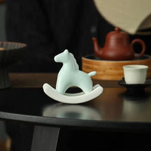 Load image into Gallery viewer, This Petite Ceramic Rocking Horse by Allthingscurated is a work of art. Crafted by hand from ceramic and decorated with a beautiful crackle pattern, it exudes a subtle far-eastern beauty and grace. Makes a perfect gift for those who appreciate quality craftsmanship and a treasured gift to any horse collector. Comes in green and azurerish white. Measures 9.8cm or 3.8 inches in height, 10.4cm or 4 inches in width and 4.2cm or 1.6 inches in depth.