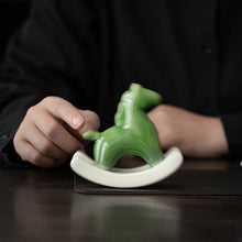 Load image into Gallery viewer, This Petite Ceramic Rocking Horse by Allthingscurated is a work of art. Crafted by hand from ceramic and decorated with a beautiful crackle pattern, it exudes a subtle far-eastern beauty and grace. Makes a perfect gift for those who appreciate quality craftsmanship and a treasured gift to any horse collector. Comes in green and azurerish white. Measures 9.8cm or 3.8 inches in height, 10.4cm or 4 inches in width and 4.2cm or 1.6 inches in depth.
