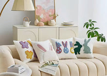 Load image into Gallery viewer, Decorative pillows with colorful patterns on a beige sofa in a living room setting. Spring Melody Embroidered Cushion Covers by Allthingscurated feature charming seasonal details to transition your home into Spring and Easter effortlessly. Each cover showcases meticulous embroidery to add depth and visual interest to your sofa and furniture.