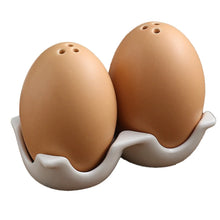 Load image into Gallery viewer, Brown Egg Salt Pepper Shaker Set by Allthingscurated are made of high-quality ceramic and designed to resemble real eggs. These shakers come with a try to securely hold them in place. Perfect for your Easter table or as a thoughtful housewarming gift.