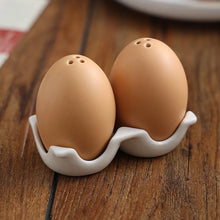 Load image into Gallery viewer, Brown Egg Salt Pepper Shaker Set by Allthingscurated are made of high-quality ceramic and designed to resemble real eggs. These shakers come with a try to securely hold them in place. Perfect for your Easter table or as a thoughtful housewarming gift.